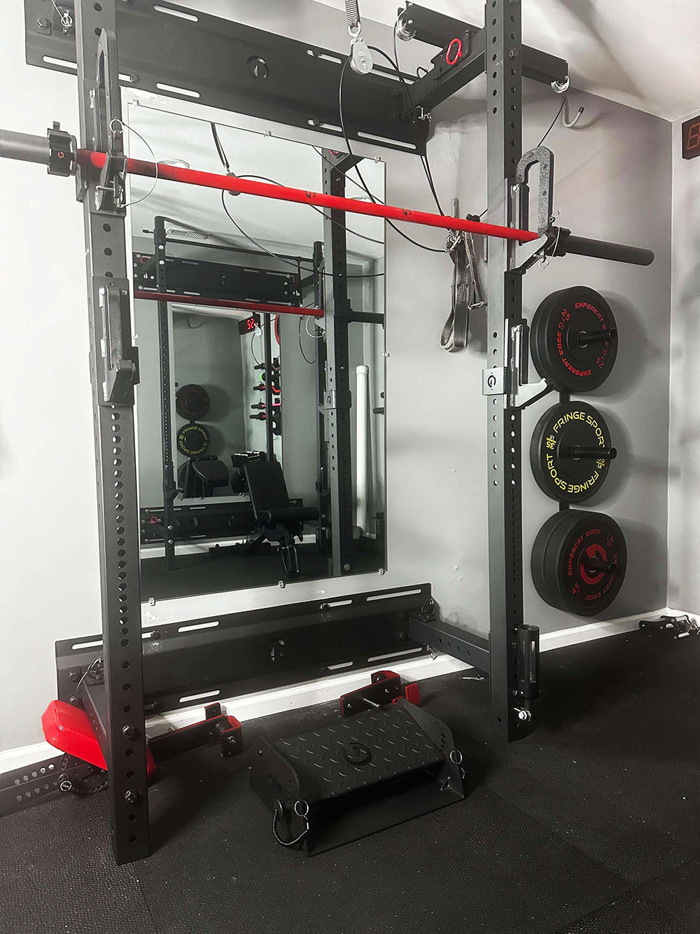 The Adjustable Calf Raise Block and Calf Cup Set are the perfect combination for calf workouts. This image presents The Calf Cups holding a barbell with the Adjustable Calf Raise Block placed on the ground below the barbell.