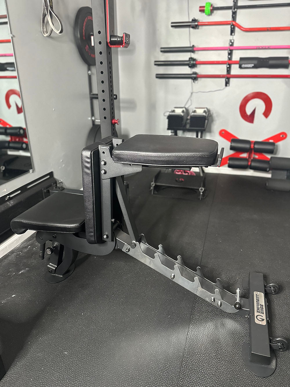 The Edge Infinity Bench is a bench that combines three separate benches all into one bench. You get the benefits of a flat bench, incline bench, and half bench all in one device. This image presents the bench from a side view with the head support adjusted to create space for behind the head workouts.