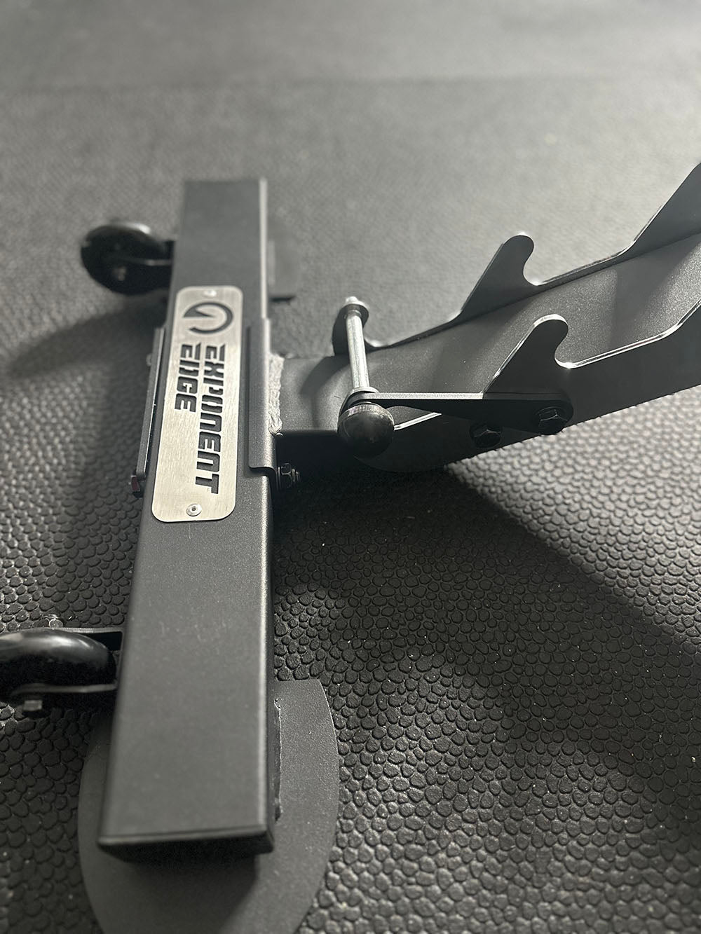 The Edge Infinity Bench is a bench that combines three separate benches all into one bench. You get the benefits of a flat bench, incline bench, and half bench all in one device. This image shows a close of view of one of the support legs with the Exponent Edge logo engraved..
