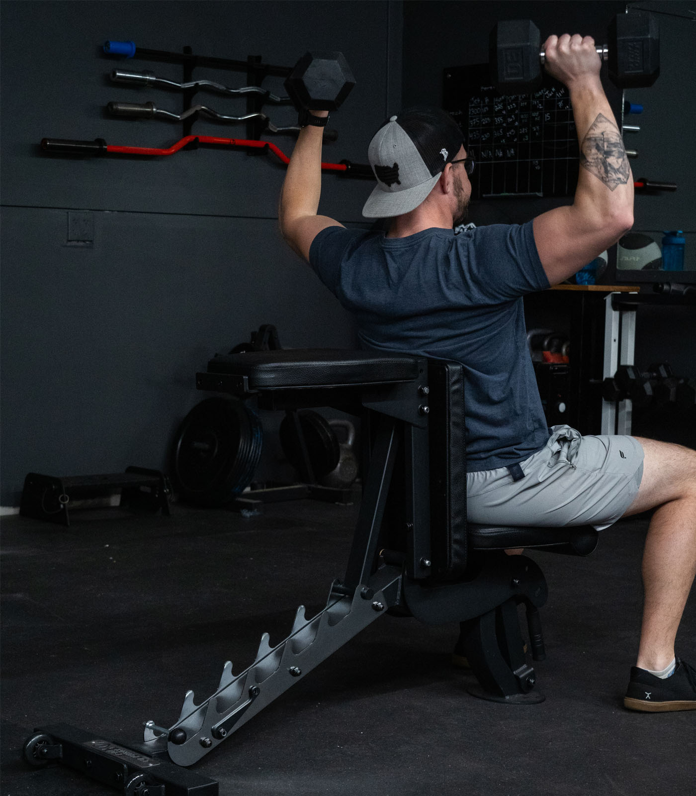 Man performing overhead shoulder press with the Infinity Bench configured as a half bench