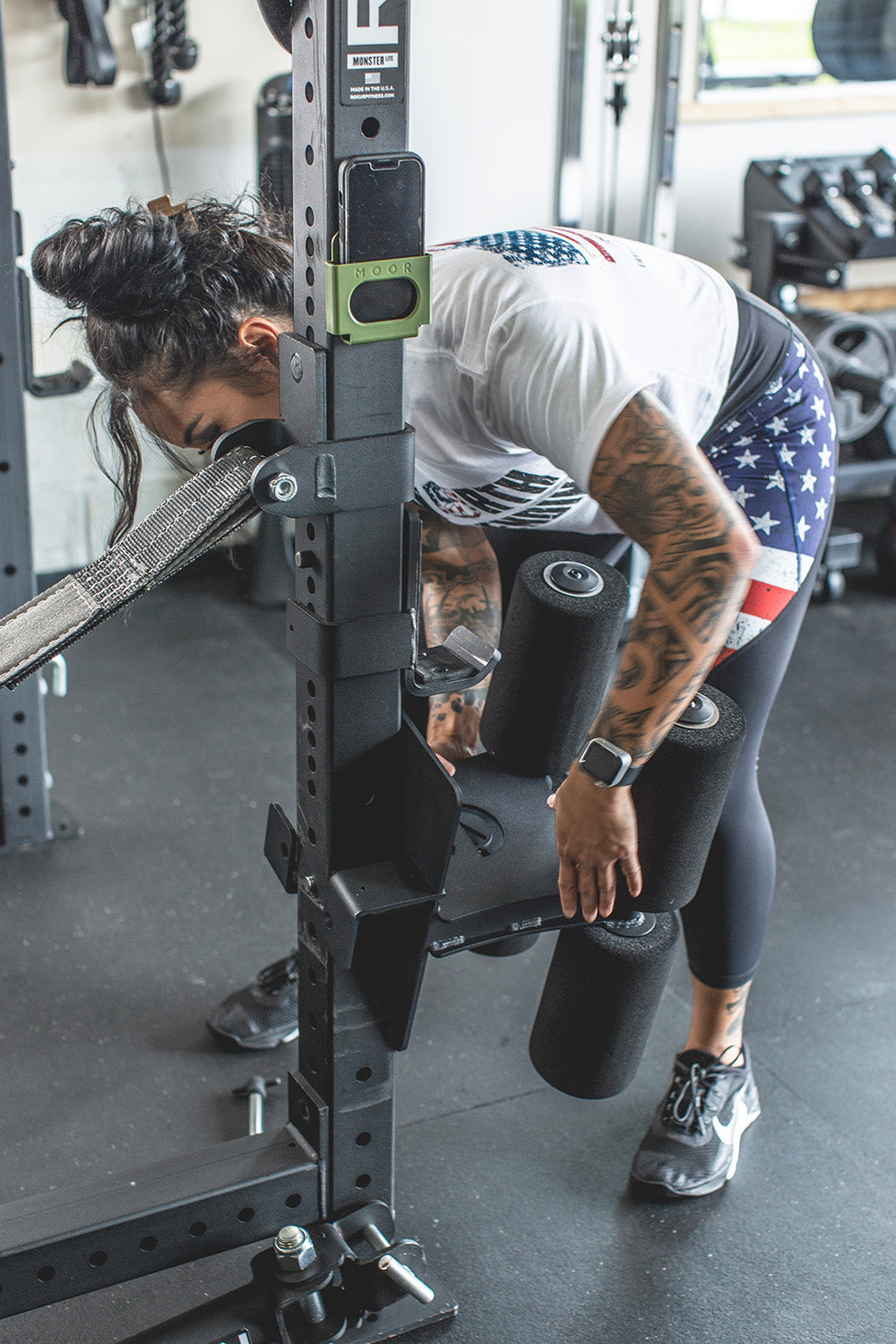 This Rack Mounted Glute Ham Developer is less bulky and lower priced than conventional GHDs. Perfect for glute workouts, ab workouts, and hamstring workouts. This image presents the Rack Mounted Glute Ham Developer being attached to a power rack in a home gym.