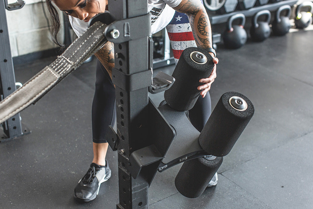 This Rack Mounted Glute Ham Developer is less bulky and lower priced than conventional GHDs. Perfect for glute workouts, ab workouts, and hamstring workouts. This image presents the Rack Mounted Glute Ham Developer being attached to a power rack in a home gym.