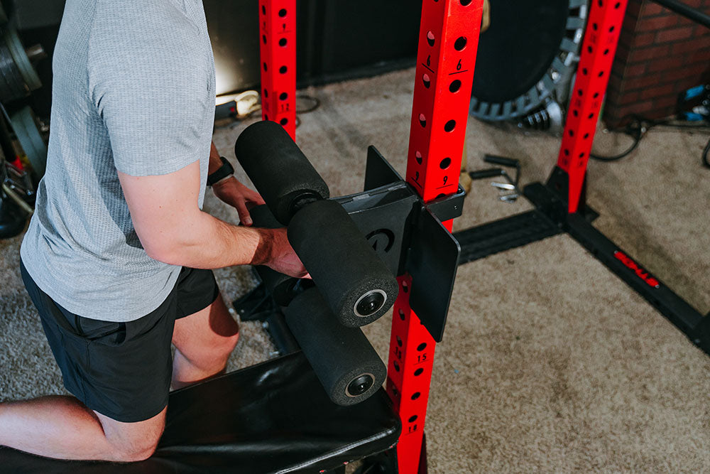 This Rack Mounted Glute Ham Developer is less bulky and lower priced than conventional GHDs. Perfect for glute workouts, ab workouts, and hamstring workouts. This image presents the Rack Mounted Glute Ham Developer being attached to a power rack.